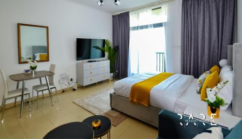 a bedroom with a bed and a table and a tv at Rare Holiday Homes welcomes you in - Canal View - The links canal Apartment R304 in Dubai