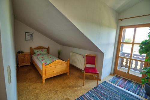 een slaapkamer met een bed, een stoel en een raam bij Ferienwohnung-auf-dem-Bauernhof-fuer-4-oder-5-Personen-im-Herzen-Niederbayerns in Mamming
