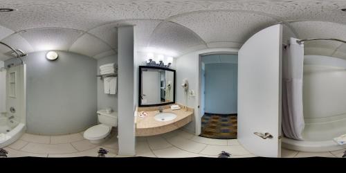 a bathroom with a toilet and a tub and a sink at Baymont by Wyndham - Chicago - Addison - O'Hare in Addison