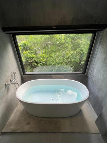 a bath tub in a bathroom with a window at Luancharoen Home Resort Phuket in Thalang