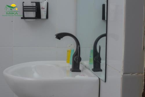 a sink with two faucets in a bathroom at Miika Guest House in Entebbe