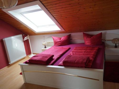 Schlafzimmer mit einem Bett mit roter Bettwäsche und einem Dachfenster in der Unterkunft Haus Irmgard in Zell am Harmersbach