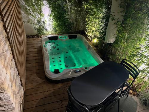 a hot tub on a deck with a table and a chair at Villa MaRisKa et son Spa, avec balcon in Ouistreham