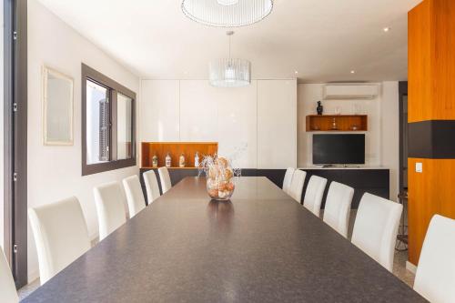 a dining room with a long table and white chairs at Villa Diagonal in Can Picafort