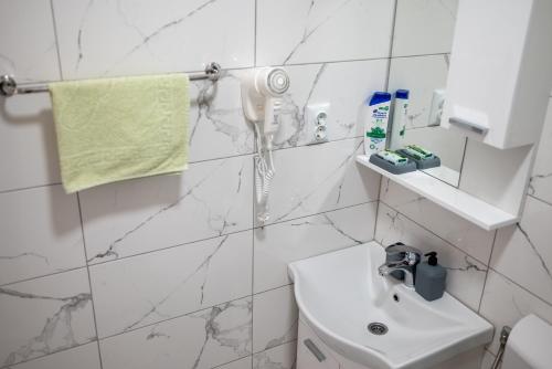 a white tiled bathroom with a sink and a phone at Felicita Apartments Brcko in Brčko