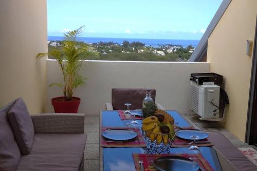 een tafel met een fruitschaal op een balkon bij Nout Zolie Vue in La Saline les Bains