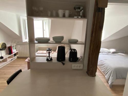 une chambre avec un lit et quelques plats sur les étagères dans l'établissement Le cocon perché entre l'Opéra et les Tuileries, à Paris