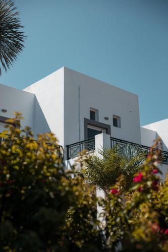 a white building with trees in front of it at Lambis Studios & Apartments in Líndos