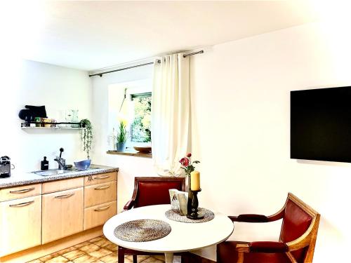 a kitchen with a table and chairs and a tv at GastRoom Am Seefeld in Grafing