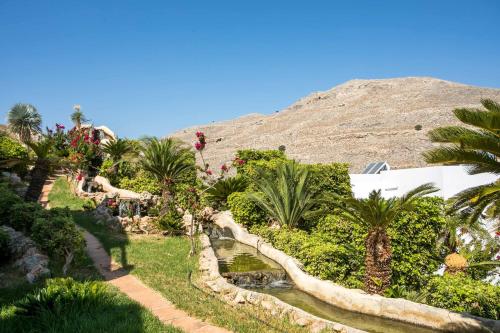 a garden with palm trees and a mountain in the background at Lambis Studios & Apartments in Líndos