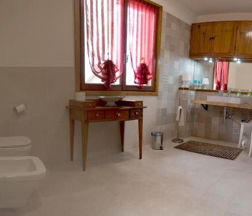 a bathroom with a toilet and a window with red curtains at Bed&Breakfast 26 in Casinalbo