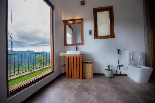 a bathroom with a toilet and a large window at Dowa Elegance Resort in Ella