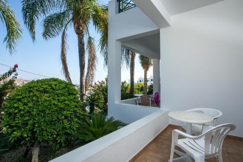 a balcony with a table and chairs and palm trees at Lambis Studios & Apartments in Líndos