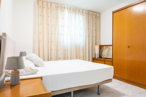 a bedroom with a white bed and a wooden cabinet at GuestReady - Vintage Elegance in Catalonia in Cornellà de Llobregat