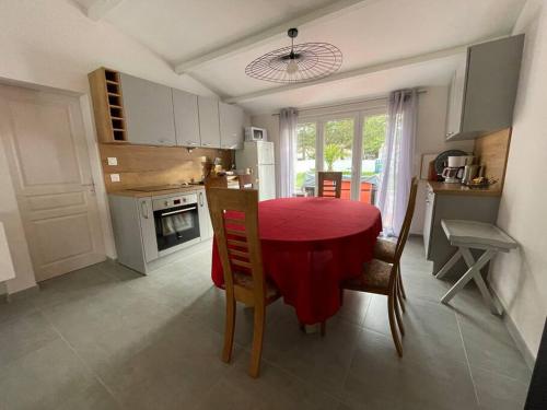 una cocina con una mesa con un mantel rojo. en Maison, 150 m de la plage, la Tresson,Noirmoutier, en La Guérinière