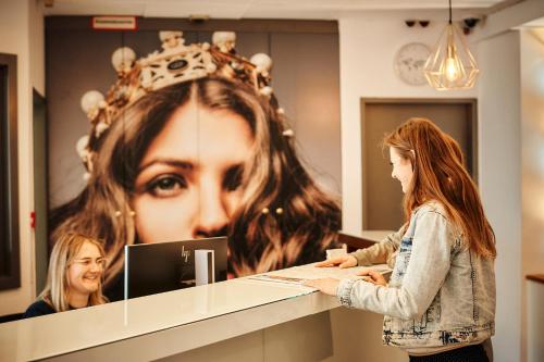 a woman standing at a counter in front of a mirror at Hotel Calmo in Vienna