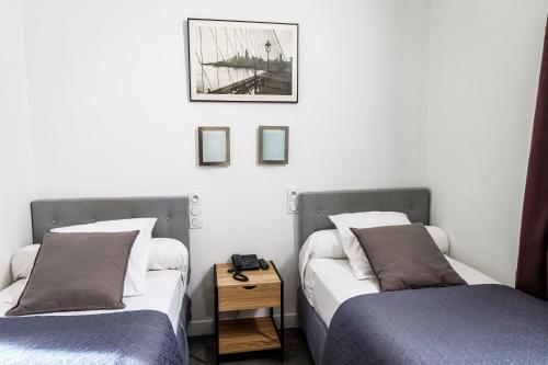 two beds sitting next to each other in a room at Hotel Du Dauphiné in Lyon