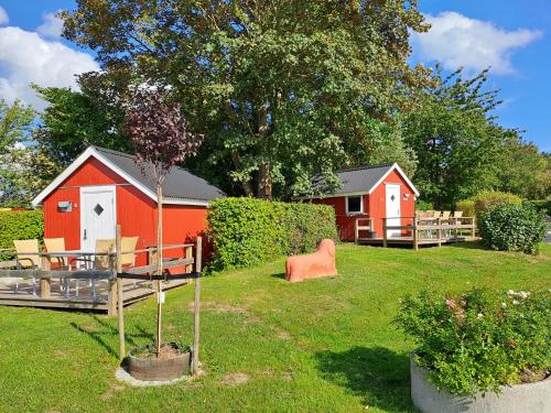 a backyard with a red house and a tree at Hytte - 1 rums hytter in Vig