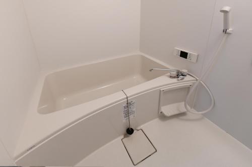 a white bathroom with a bath tub with a sink at JH Yellow Guest House in Tokyo