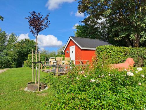 a red shed in a field next to a garden at Hytte - 1 rums hytter in Vig