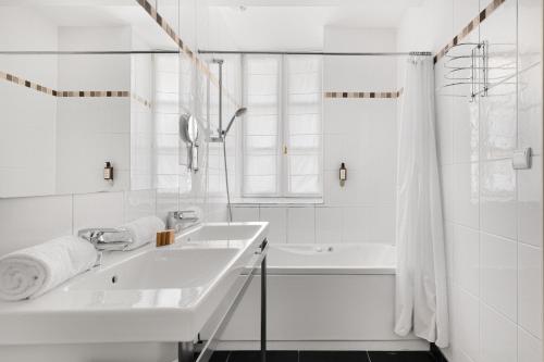 a white bathroom with a sink and a tub at Le Phénix Hôtel in Lyon