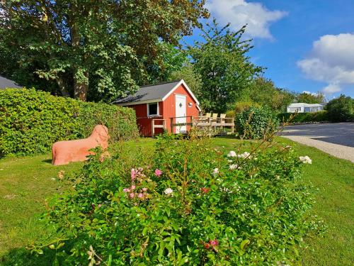 a small red house in a yard with a bush at Hytte - 1 rums hytter in Vig