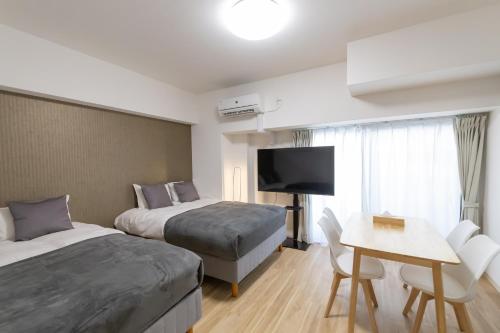 a hotel room with two beds and a table and a tv at Ocean Tsutenkaku in Osaka