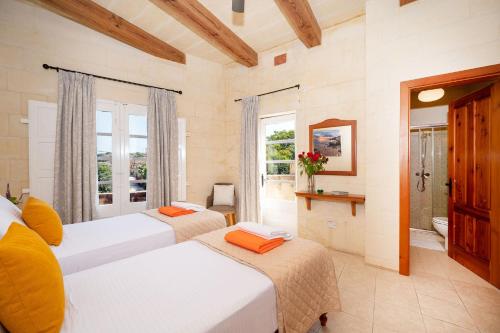 a bedroom with two beds and a bathroom with a window at Veduta Holiday Home in Qala