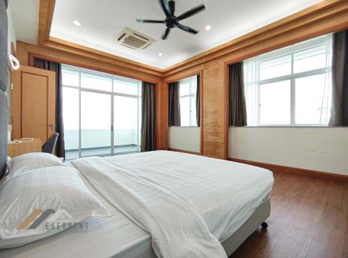 a bedroom with a bed with windows and a ceiling fan at Bay Resort Penthouse by Evernent in Miri