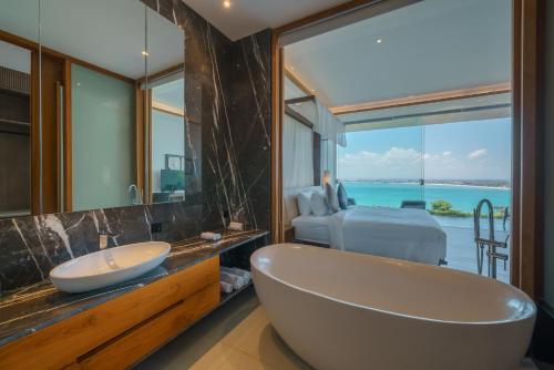 ein Badezimmer mit Badewanne und ein Schlafzimmer mit Aussicht in der Unterkunft Beyond The Sea - Luxe Sea View Villa in Jimbaran in Jimbaran