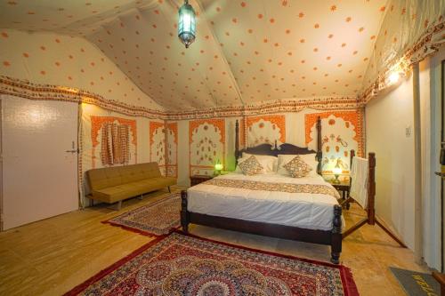 Hilton Jaisalmer Desert camp في Sām: غرفة نوم بسرير واريكة