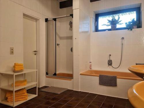 La salle de bains est pourvue d'une douche, d'une baignoire et d'un lavabo. dans l'établissement Großzügiges Ferienhaus im Grünen, à Wilhelmshaven