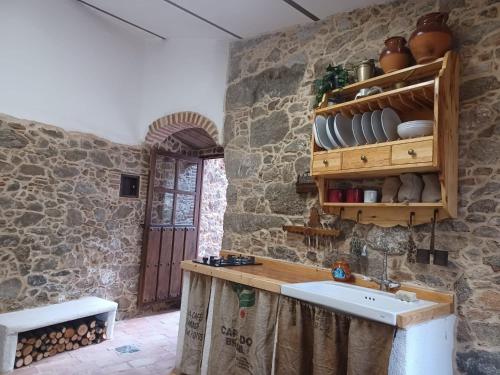 a kitchen with a sink in a stone wall at La Casita De Albino in Castillo de Bayuela