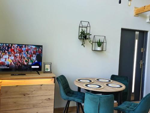a room with a table with chairs and a tv at Zielona Ostoja - domek z prywatnym pomostem przy Obrzycy in Kolsko