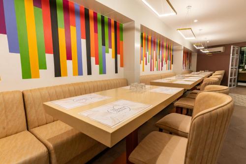 a row of tables in a restaurant with colorful art on the wall at Royal Plaza Suites by RAK Rooms, Mangaluru in Mangalore