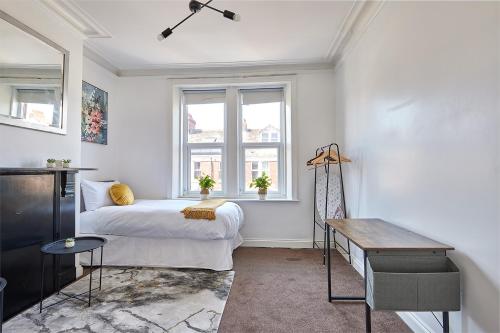 a bedroom with a bed and a desk and a window at CityHost Apartments - Gateshead 115 in Gateshead