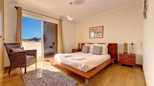 Un dormitorio con una cama y una silla y una ventana. en Lucy Sweet Home by LovelyStay, en Caniço