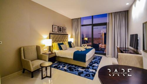 a hotel room with a bed and a chair at Rare Holiday Homes - Modern apartment - Near EXPO City - Desert view in Dubai