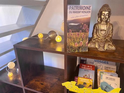 a shelf with a buddha statue and books on it at Le P'tit Rupt Refuge cocooning in Rupt-sur-Moselle