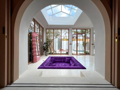 eine lila Couch in der Mitte eines Zimmers mit Fenstern in der Unterkunft No Rush Villas in Canggu
