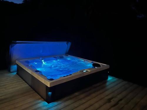 a hot tub sitting on a wooden floor with a blue at Les Deltas du Lac in Chambon-sur-Lac
