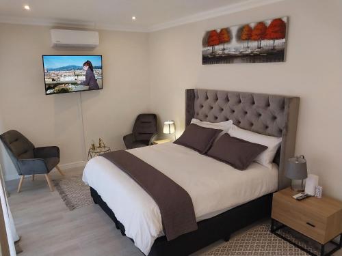 um quarto com uma cama e uma televisão na parede em LND GUEST HOUSE em Bloubergstrand