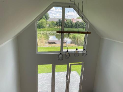 a room with a large window and a chandelier at Zielona Ostoja - domek z prywatnym pomostem przy Obrzycy in Kolsko