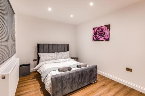 a bedroom with a bed and a purple rose painting on the wall at Business / Travelling / Relocate / Contractor Stay in Brentwood