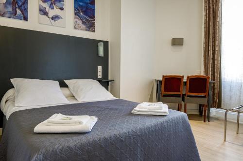 a bedroom with a bed with two towels on it at Hotel Du Dauphiné in Lyon