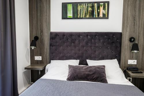 a bedroom with a large bed with a black headboard at Hotel Du Dauphiné in Lyon