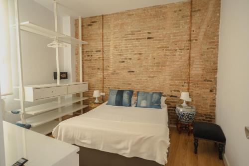1 dormitorio con cama y pared de ladrillo en Villa Conde en Hospitalet de Llobregat