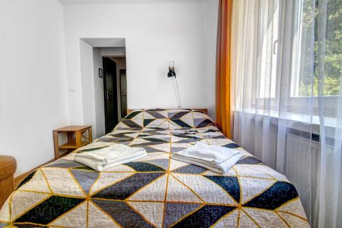 a bedroom with a bed with a quilt on it at Willa Wladyslaw - centrum Krynicy, parking w cenie! in Krynica Zdrój