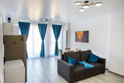 ein Wohnzimmer mit einem braunen Sofa und blauen Vorhängen in der Unterkunft Apartamente Nord 10 in Năvodari