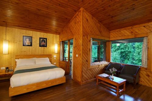 a bedroom with a bed and a chair in a room at Banon Resorts in Manāli